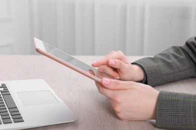 Photo of Electronic signature. Woman using tablet at wooden table, closeup