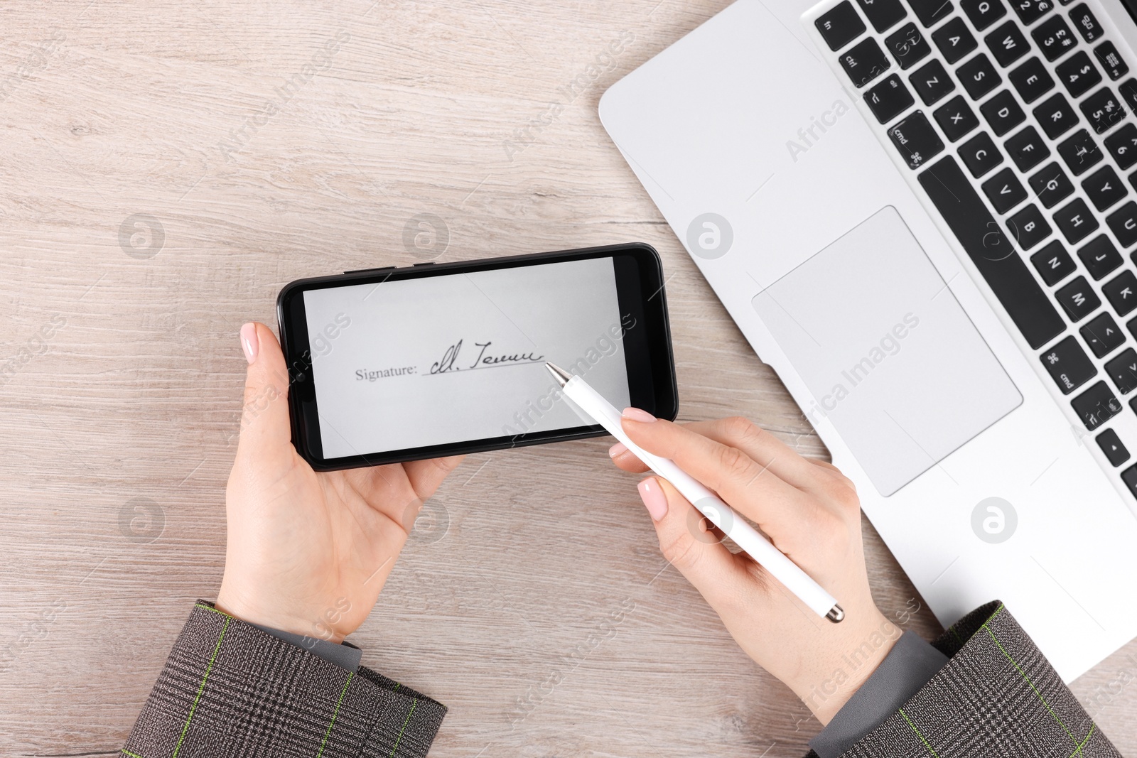 Photo of Electronic signature. Woman using stylus and smartphone at wooden table, top view