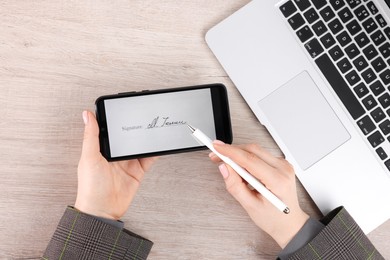 Photo of Electronic signature. Woman using stylus and smartphone at wooden table, top view