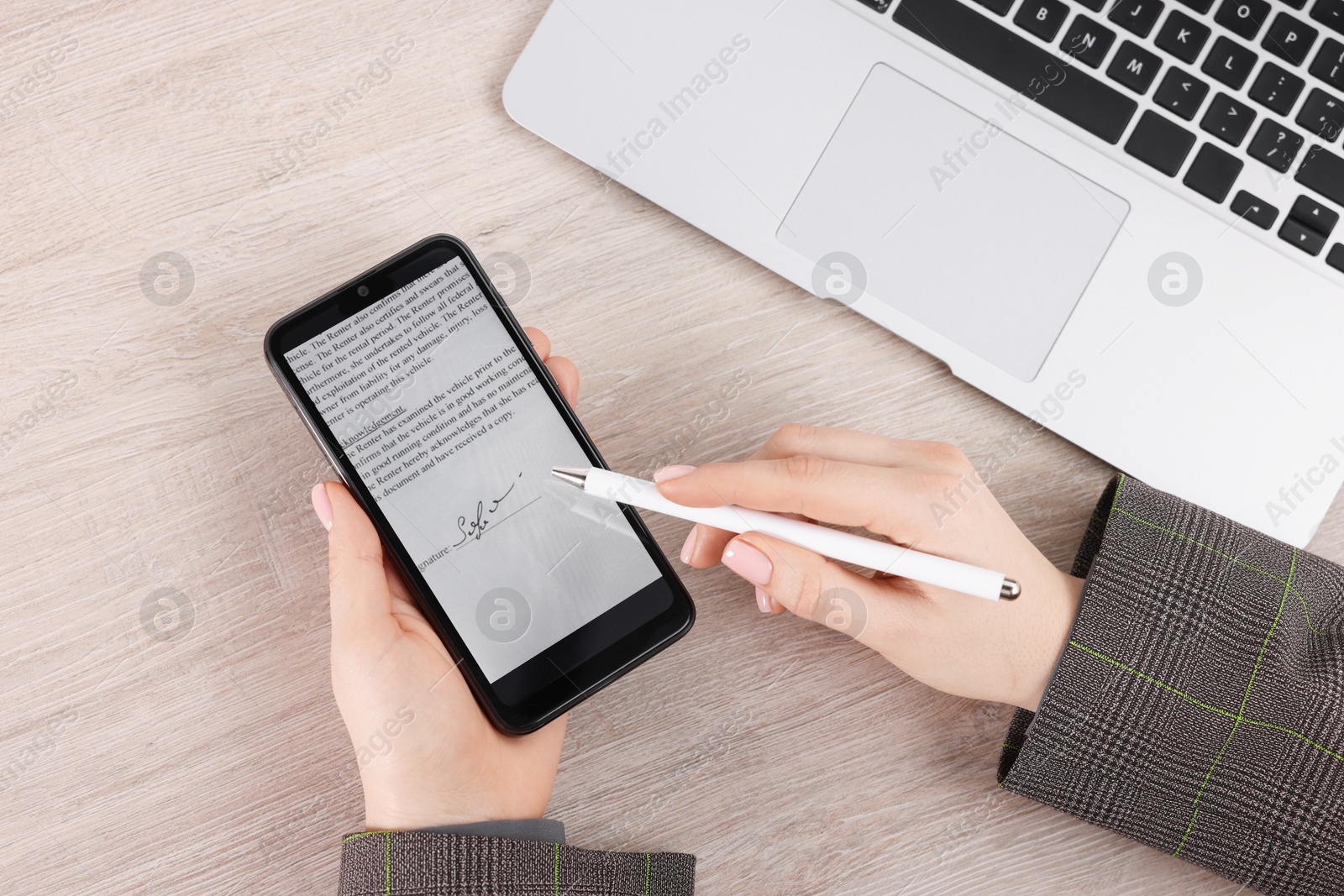 Photo of Electronic signature. Woman using stylus and smartphone at wooden table, top view