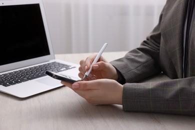 Photo of Electronic signature. Woman using stylus and smartphone at wooden table indoors, closeup