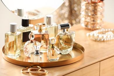 Photo of Different luxury perfumes on wooden dressing table indoors
