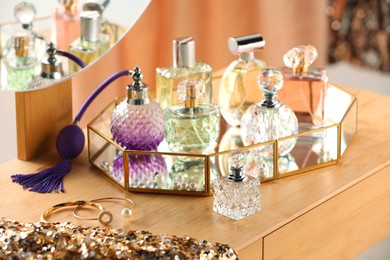 Photo of Different luxury perfumes on wooden dressing table indoors