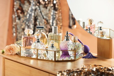 Photo of Different luxury perfumes on wooden dressing table indoors