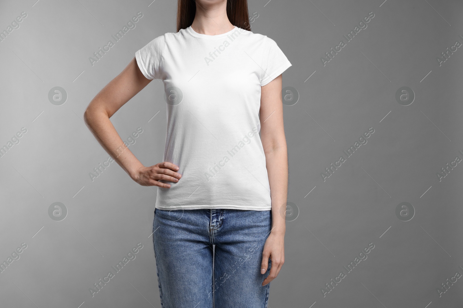 Photo of Woman wearing blank white t-shirt on light grey background, closeup. Mockup for design