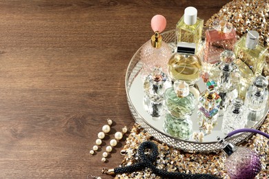 Photo of Different luxury perfumes and accessories on wooden table, space for text