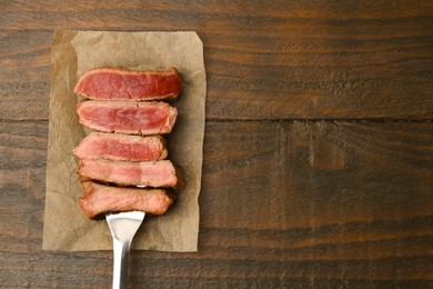 Photo of Delicious sliced beef tenderloin with different degrees of doneness on wooden table, top view. Space for text