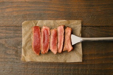 Photo of Delicious sliced beef tenderloin with different degrees of doneness on wooden table, top view