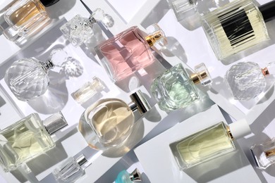 Photo of Different luxury perfumes on white background, flat lay