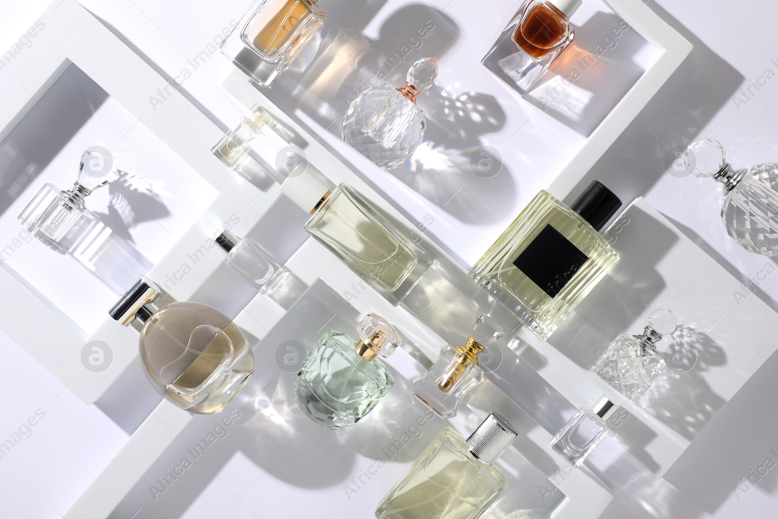 Different luxury perfumes on white background, flat lay Photo of Different luxury perfumes on white background, flat lay