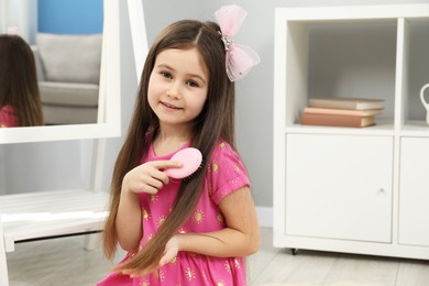 Little girl brushing her hair at home, space for text