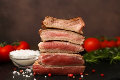 Photo of Delicious sliced beef tenderloin with different degrees of doneness and spices on table against brown background, closeup