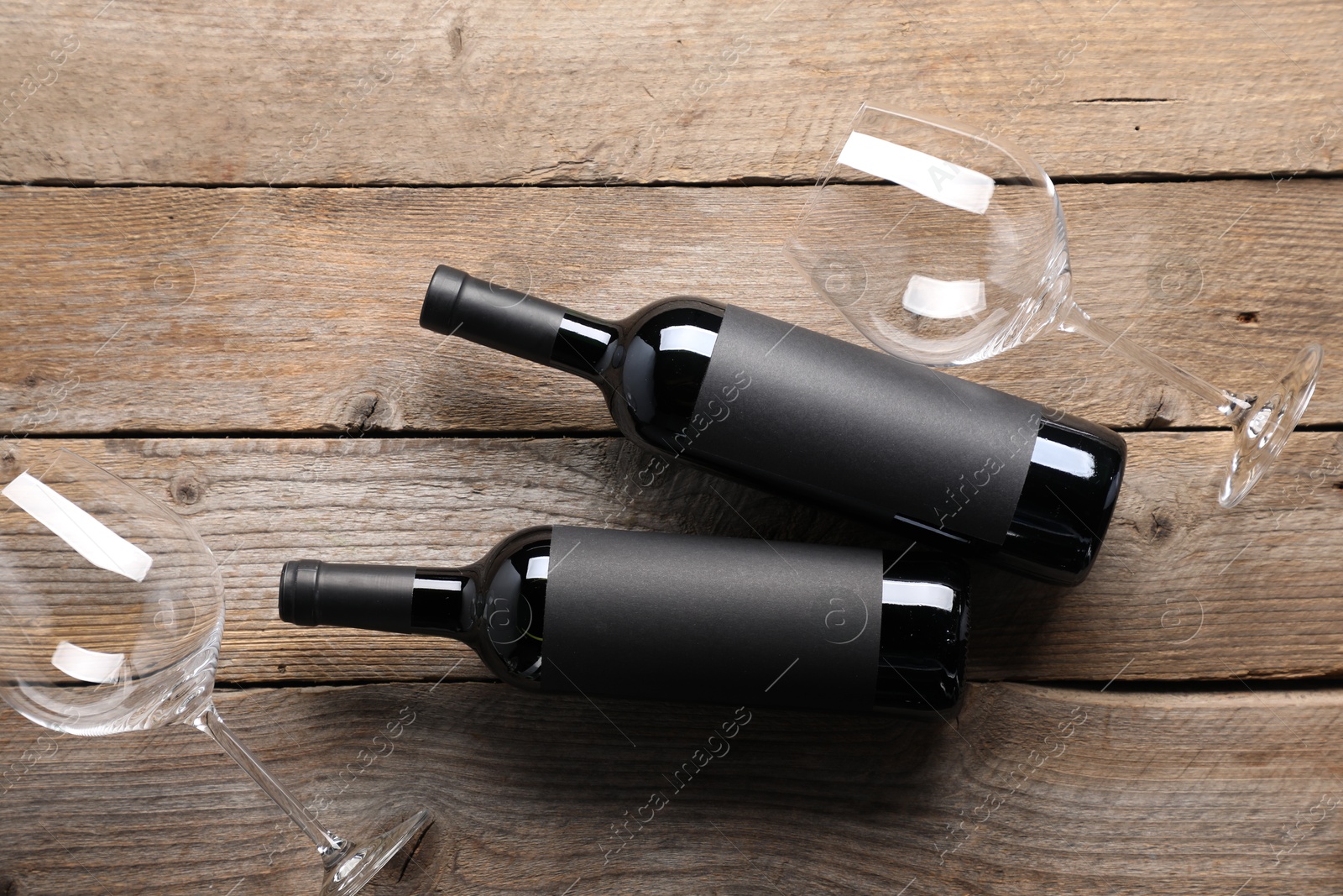 Bottles of wine and glasses on wooden table, flat lay Photo of Bottles of wine and glasses on wooden table, flat lay