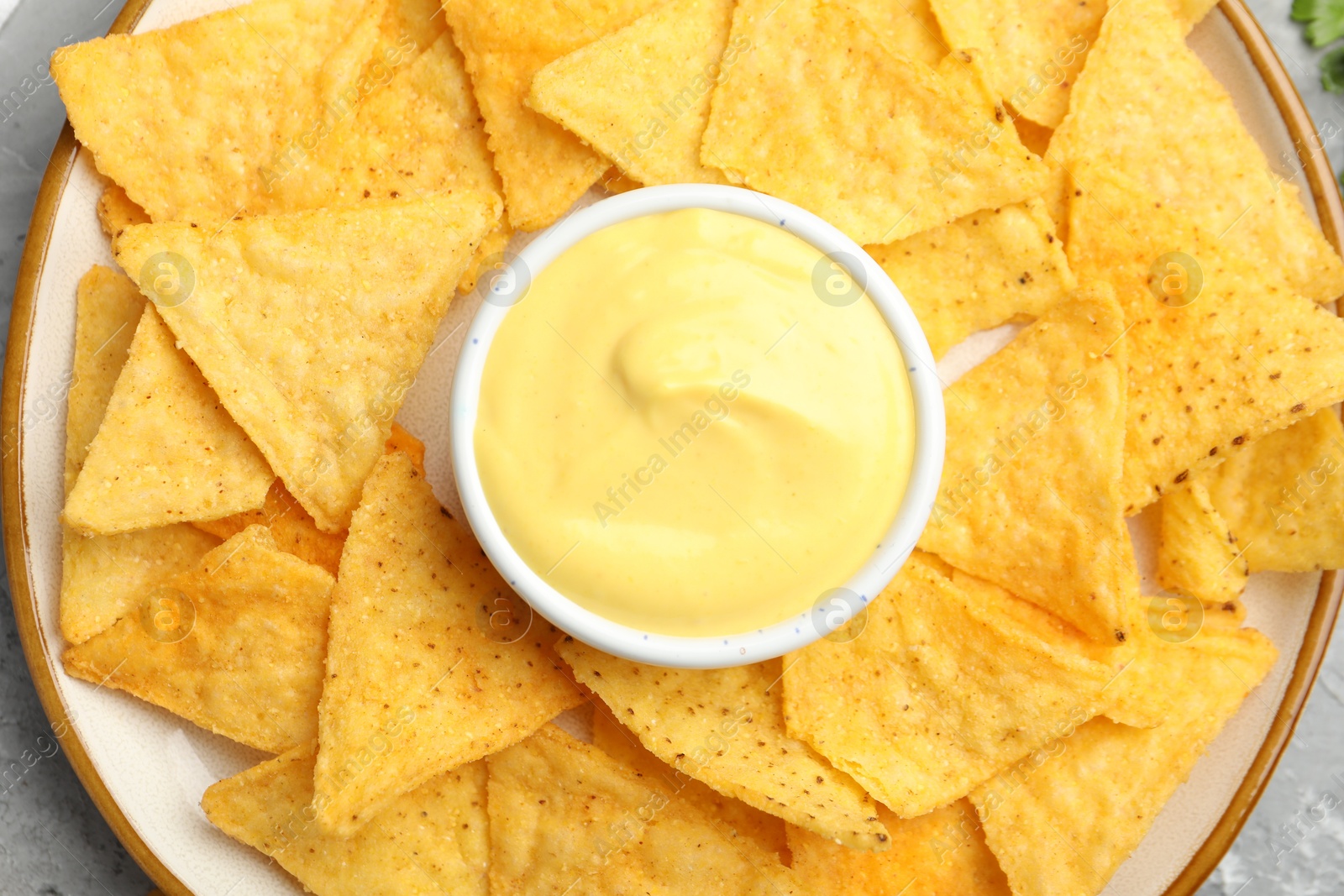 Tasty cheese dipping sauce in bowl and nacho chips on table, top view Photo of Tasty cheese dipping sauce in bowl and nacho chips on table, top view