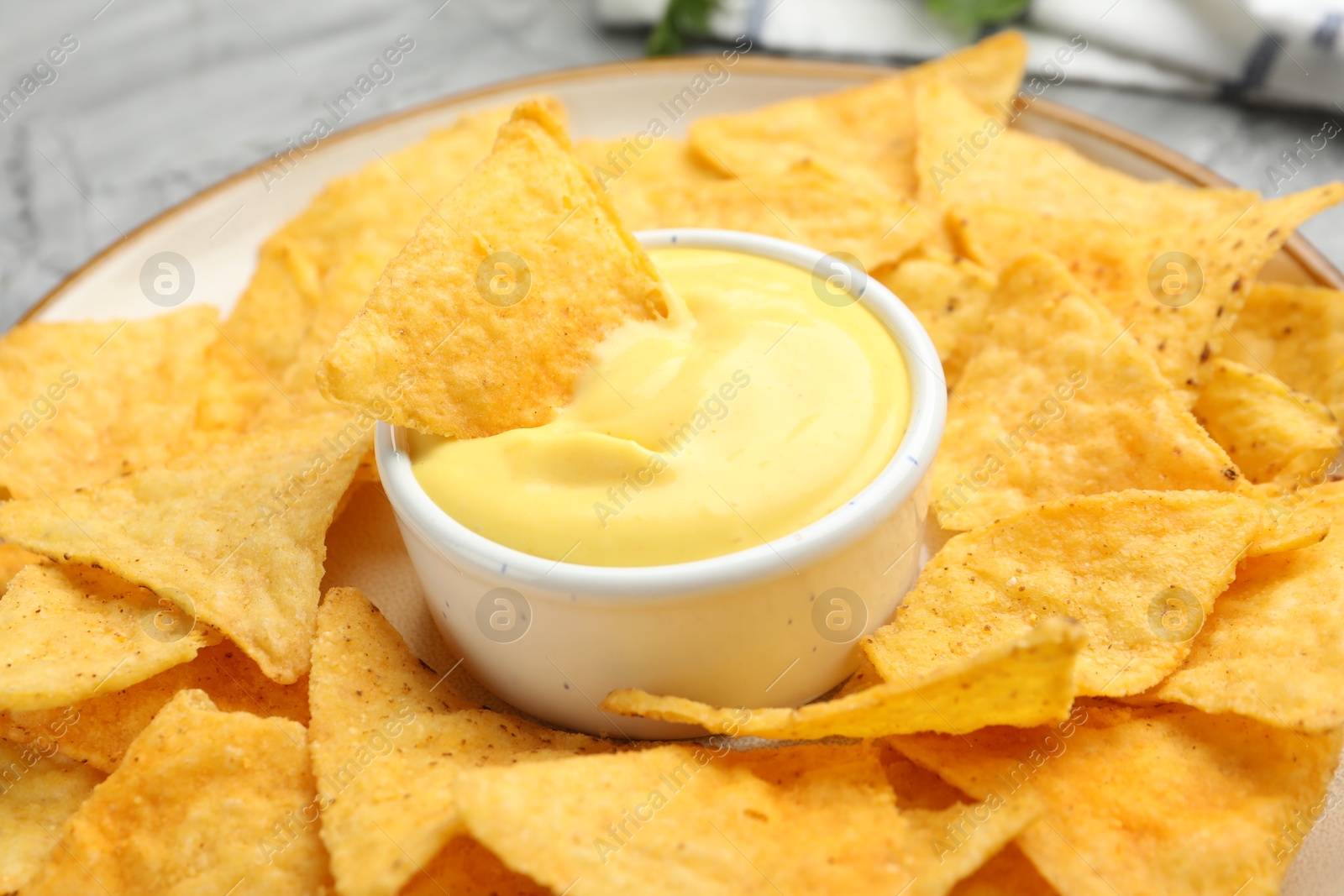 Tasty cheese dipping sauce in bowl and nacho chips on table, closeup Photo of Tasty cheese dipping sauce in bowl and nacho chips on table, closeup
