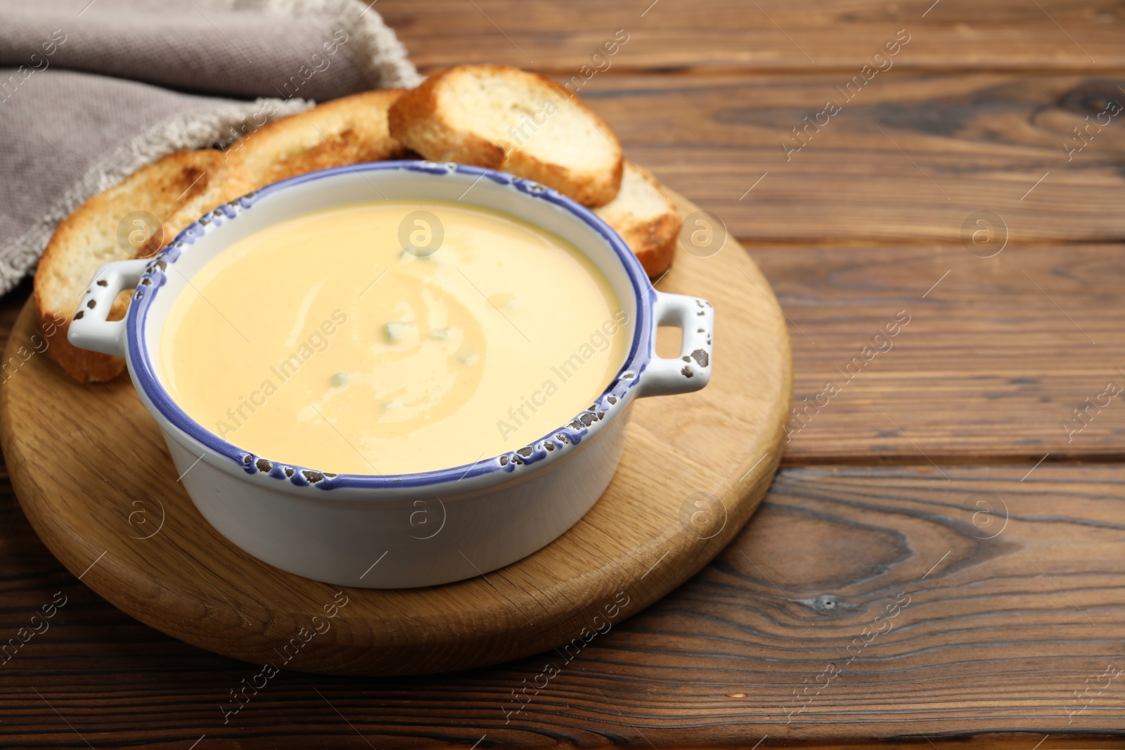 Tasty cheese dipping sauce in bowl and croutons on wooden table, closeup. Space for text Photo of Tasty cheese dipping sauce in bowl and croutons on wooden table, closeup. Space for text