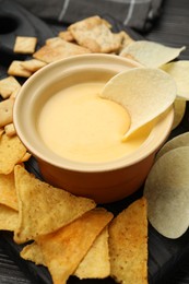 Photo of Tasty cheese dipping sauce in bowl and different snacks on table, closeup