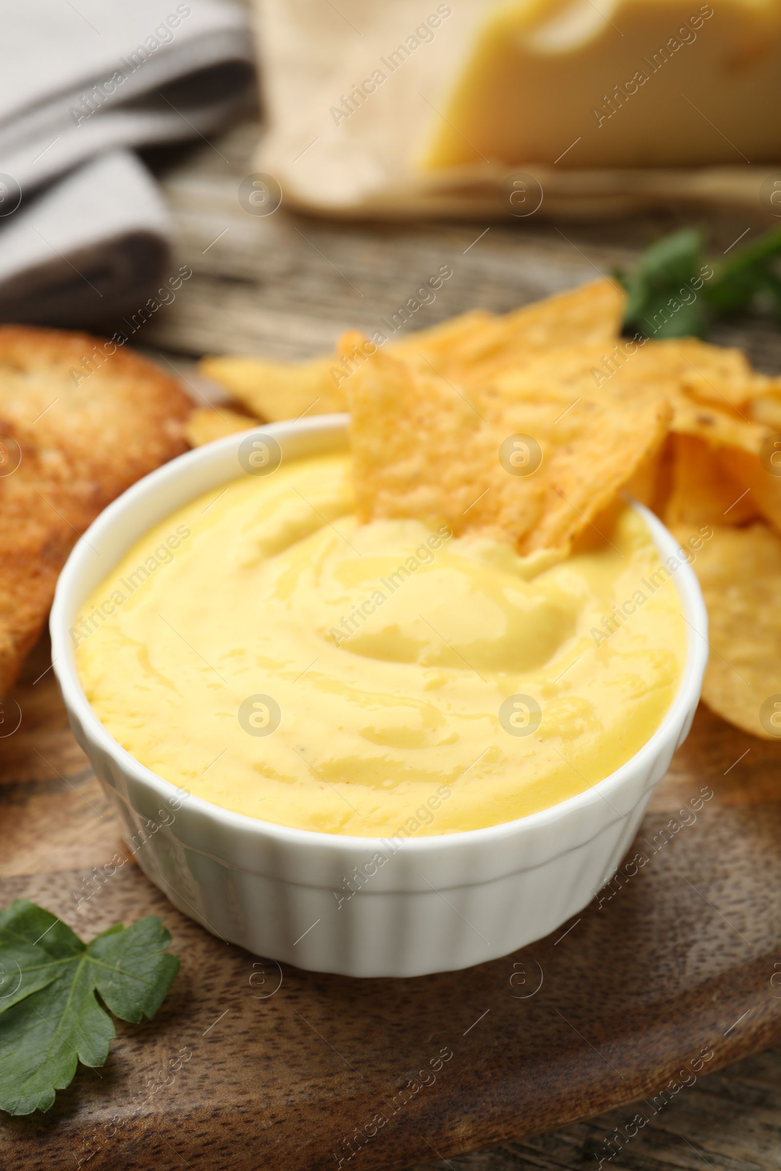 Tasty cheese dipping sauce in bowl and nacho chips on table, closeup Photo of Tasty cheese dipping sauce in bowl and nacho chips on table, closeup
