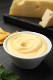 Photo of Tasty dipping cheese sauce in bowl on black table, closeup