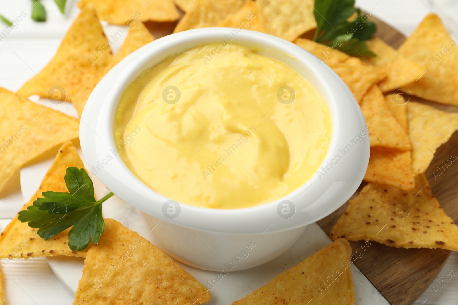 Tasty dipping cheese sauce in bowl and nacho chips on table, closeup Photo of Tasty dipping cheese sauce in bowl and nacho chips on table, closeup