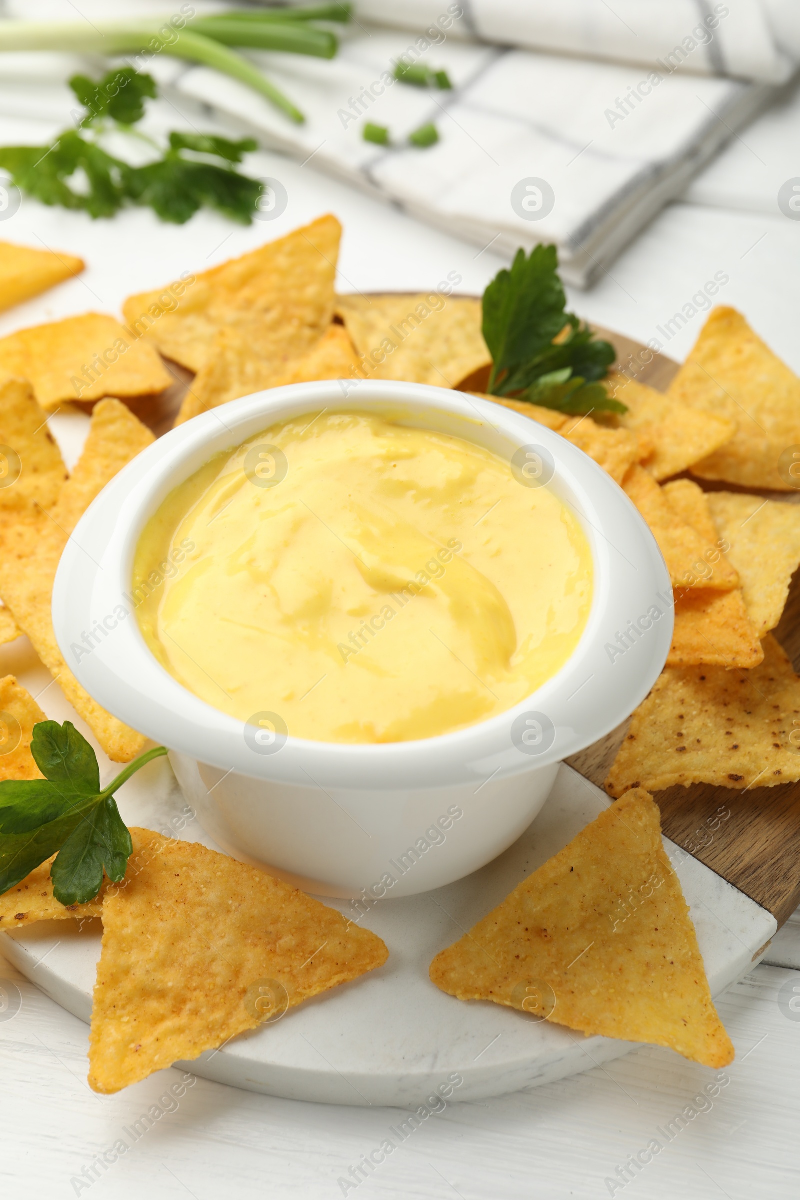 Tasty dipping cheese sauce in bowl and nacho chips on white wooden table, closeup Photo of Tasty dipping cheese sauce in bowl and nacho chips on white wooden table, closeup