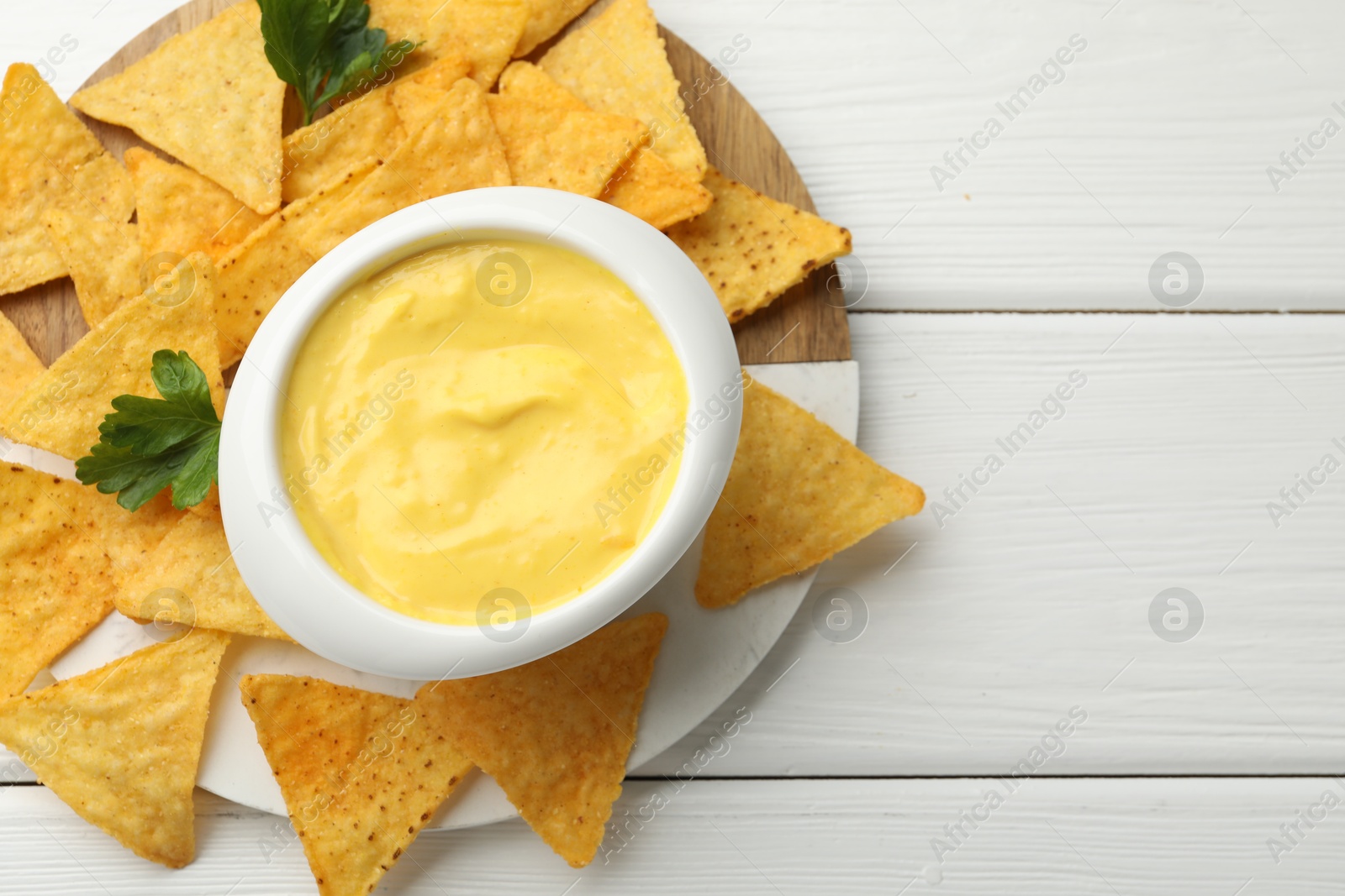 Tasty dipping cheese sauce in bowl and nacho chips on white wooden table, top view. Space for text Photo of Tasty dipping cheese sauce in bowl and nacho chips on white wooden table, top view. Space for text