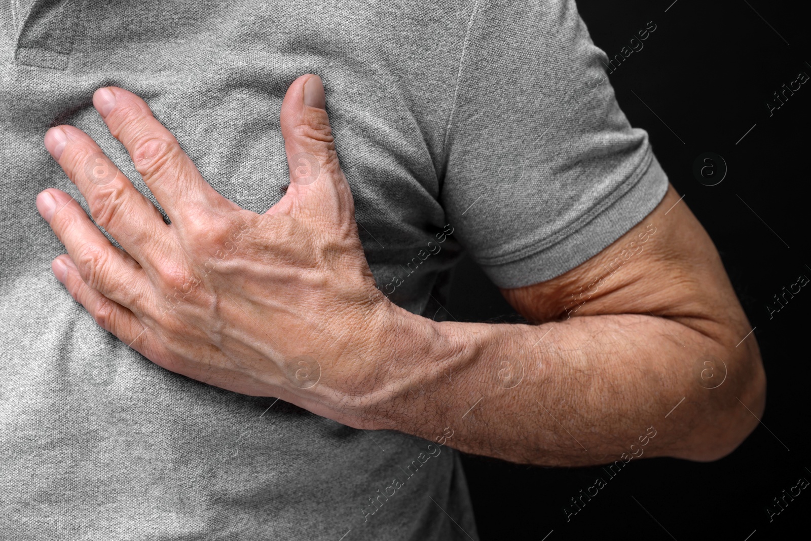 Photo of Heart attack. Senior man suffering from pain in chest on black background, closeup