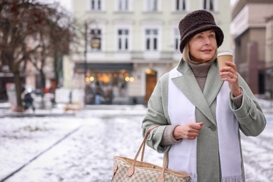 Photo of Beautiful senior woman with paper cup on city street. Space for text