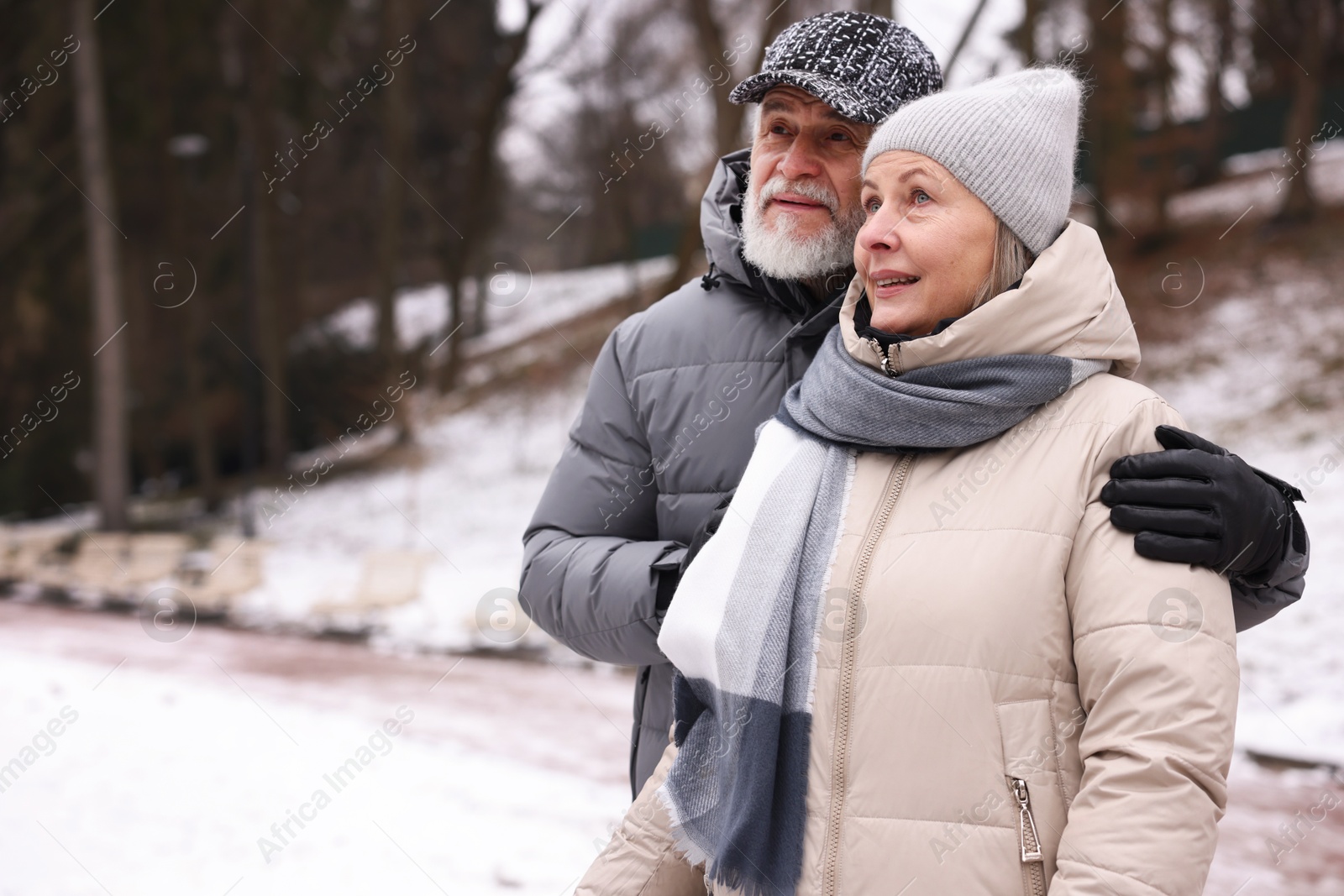 Photo of Happy senior couple walking in winter park. Space for text