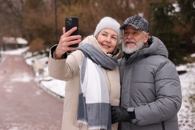 Happy senior couple taking selfie at winter park