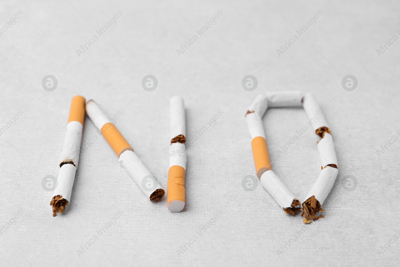 Photo of Word NO made with cigarette butts on light gray background