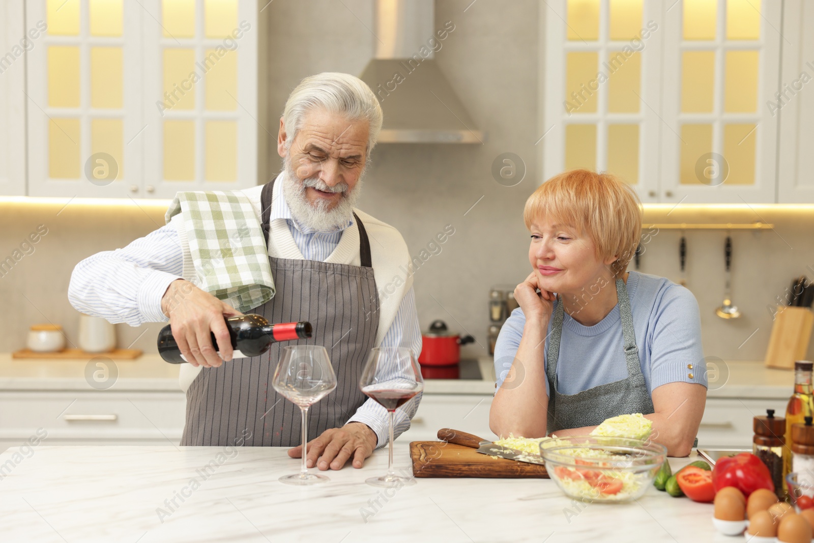 Photo of Senior couple having wine while cooking in kitchen