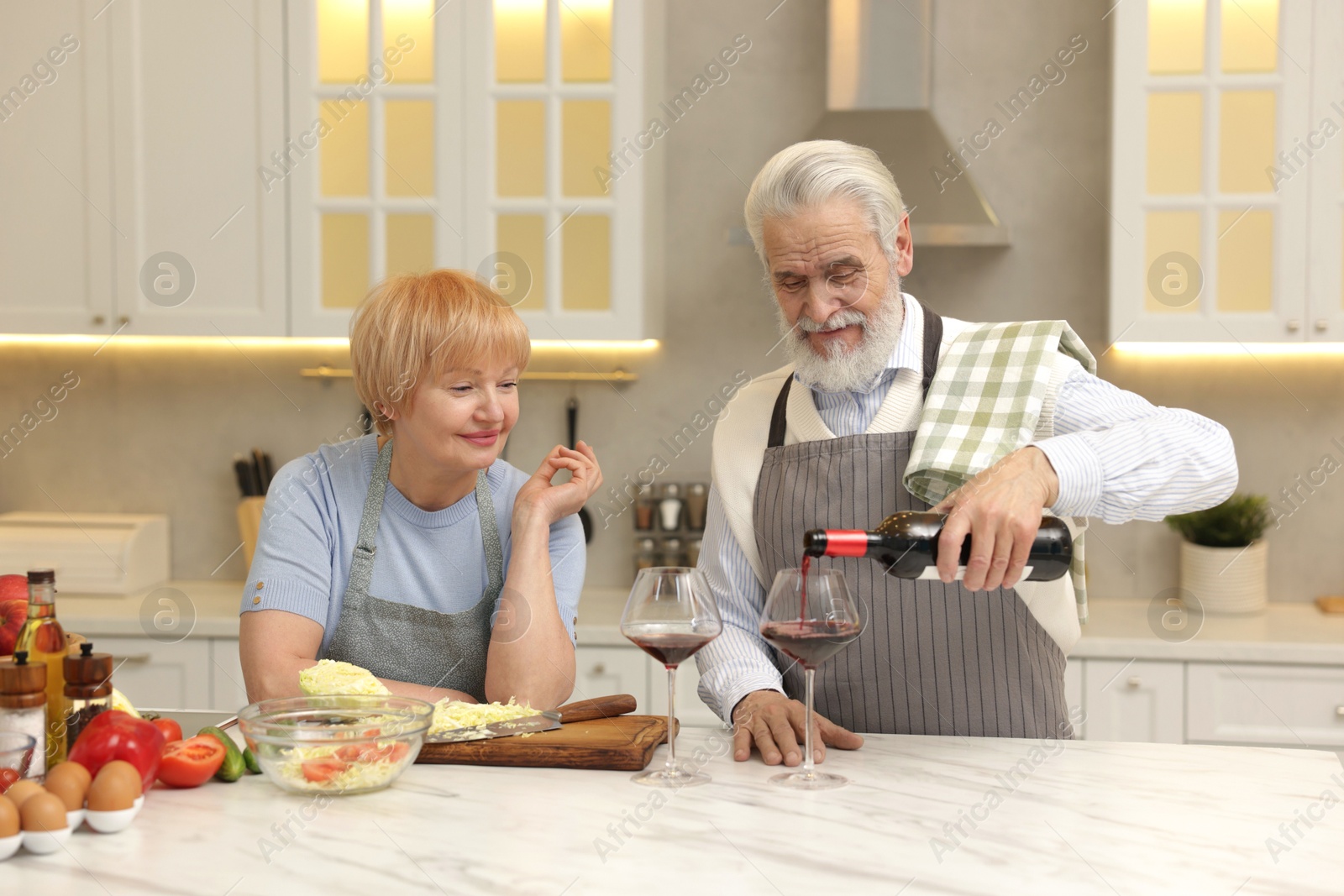 Photo of Senior couple having wine while cooking in kitchen