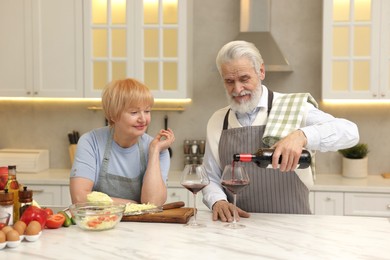 Senior couple having wine while cooking in kitchen