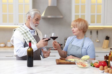 Senior couple having wine while cooking in kitchen