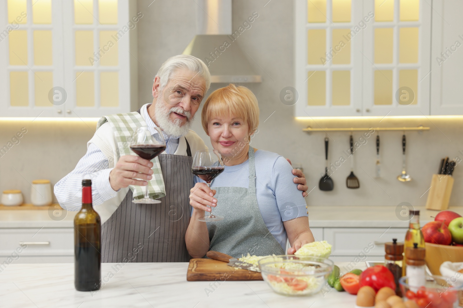 Photo of Senior couple having wine while cooking in kitchen