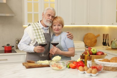 Senior couple having wine while cooking in kitchen