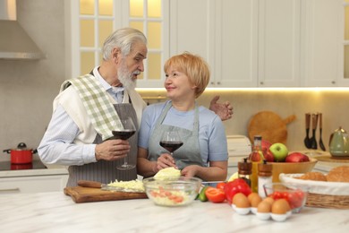 Senior couple having wine while cooking in kitchen