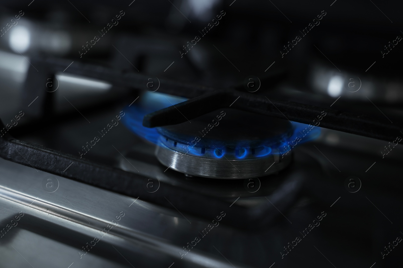 Photo of Gas burner with blue flame on stove, closeup