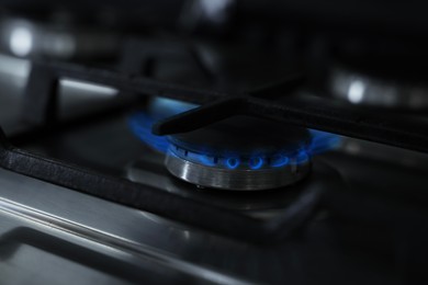 Photo of Gas burner with blue flame on stove, closeup