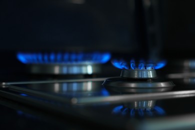 Photo of Gas burners with blue flame on stove, closeup