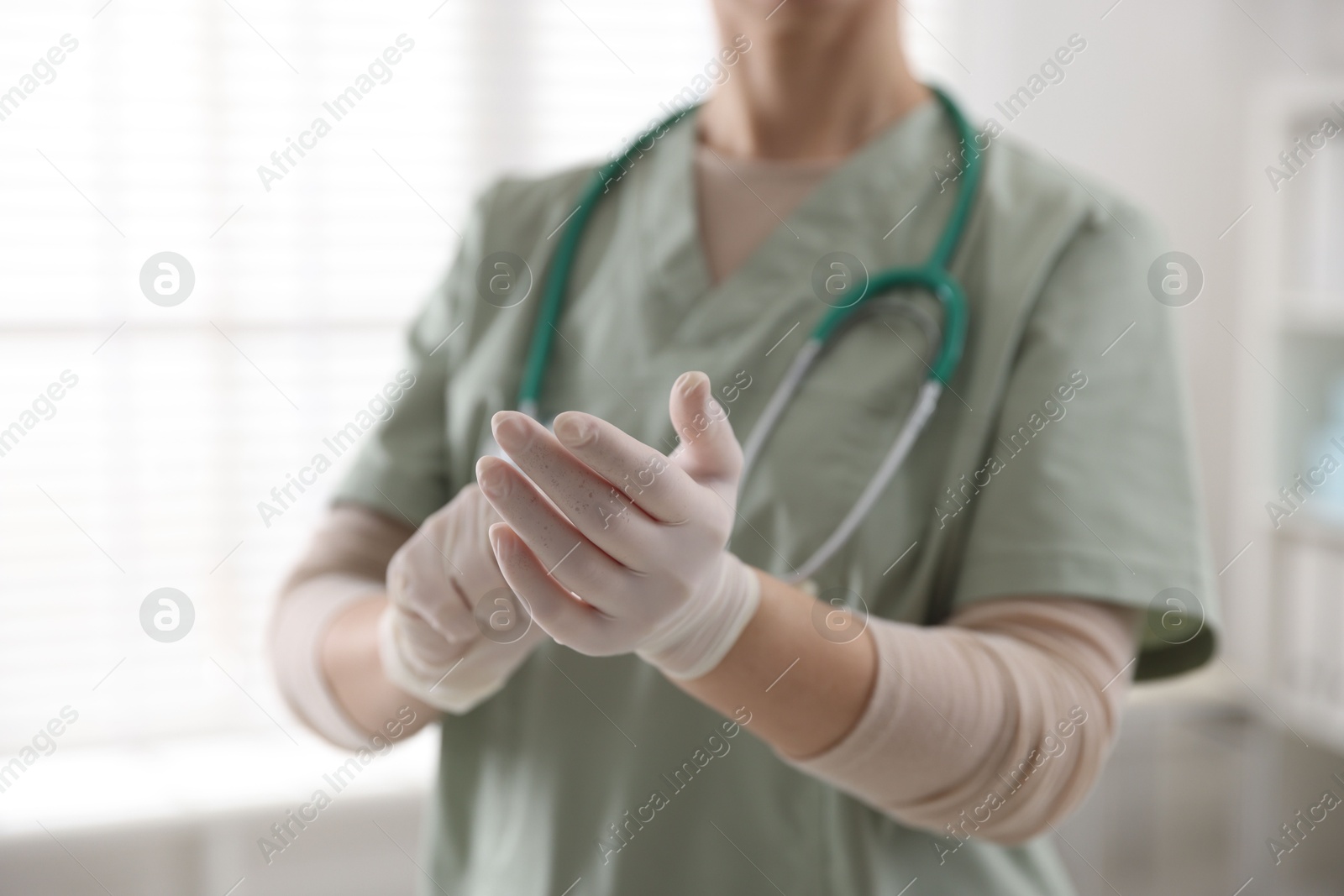 Photo of Medical worker putting gloves in hospital, closeup