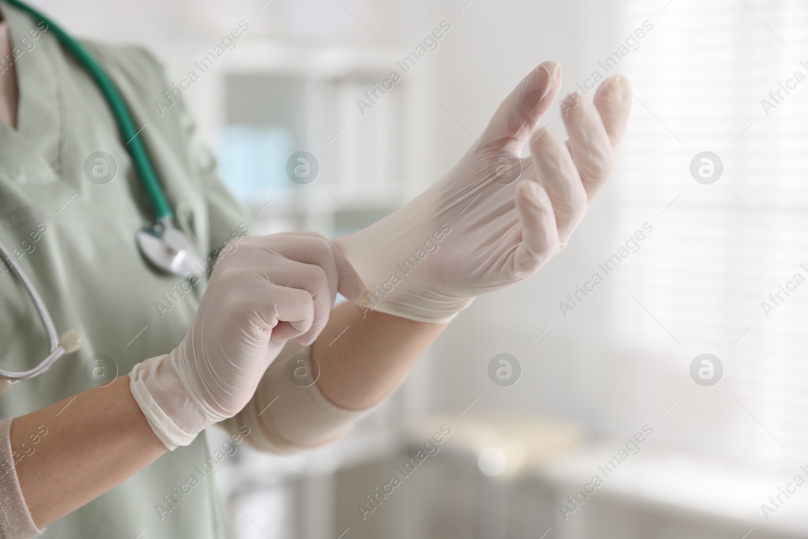 Photo of Medical worker putting gloves in hospital, closeup