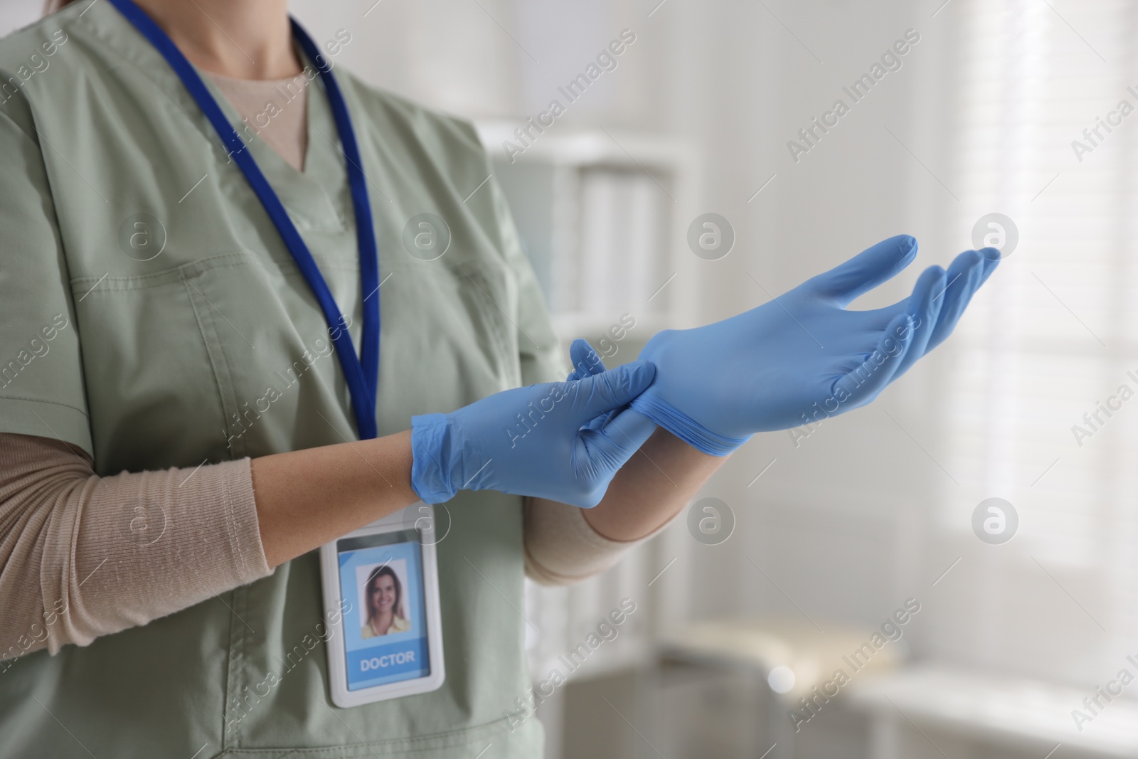 Photo of Medical worker putting gloves in hospital, closeup