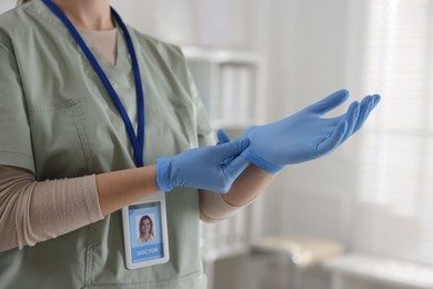 Photo of Medical worker putting gloves in hospital, closeup