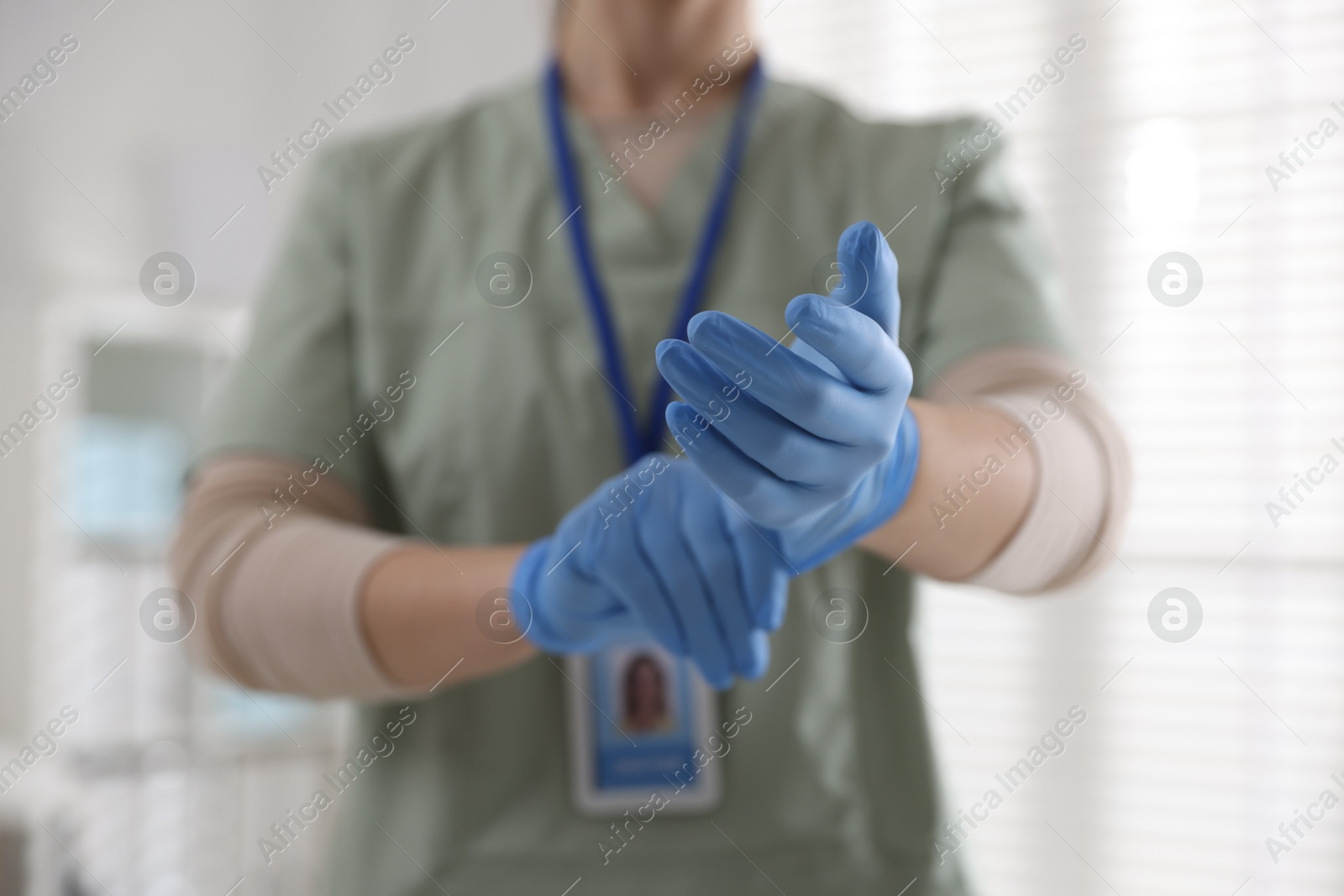 Photo of Medical worker putting gloves in hospital, closeup