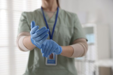 Photo of Medical worker putting gloves in hospital, closeup