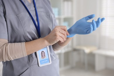 Photo of Medical worker putting gloves in hospital, closeup