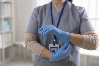 Photo of Medical worker putting gloves in hospital, closeup