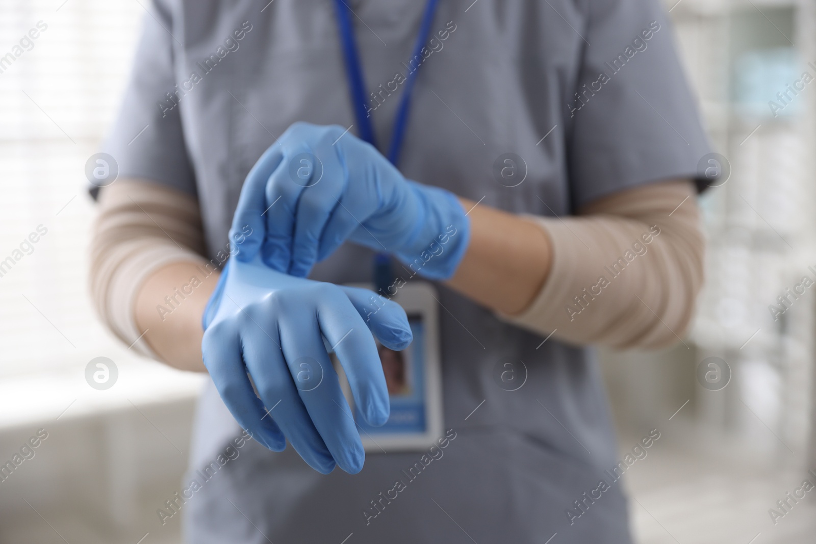 Photo of Medical worker putting gloves in hospital, closeup